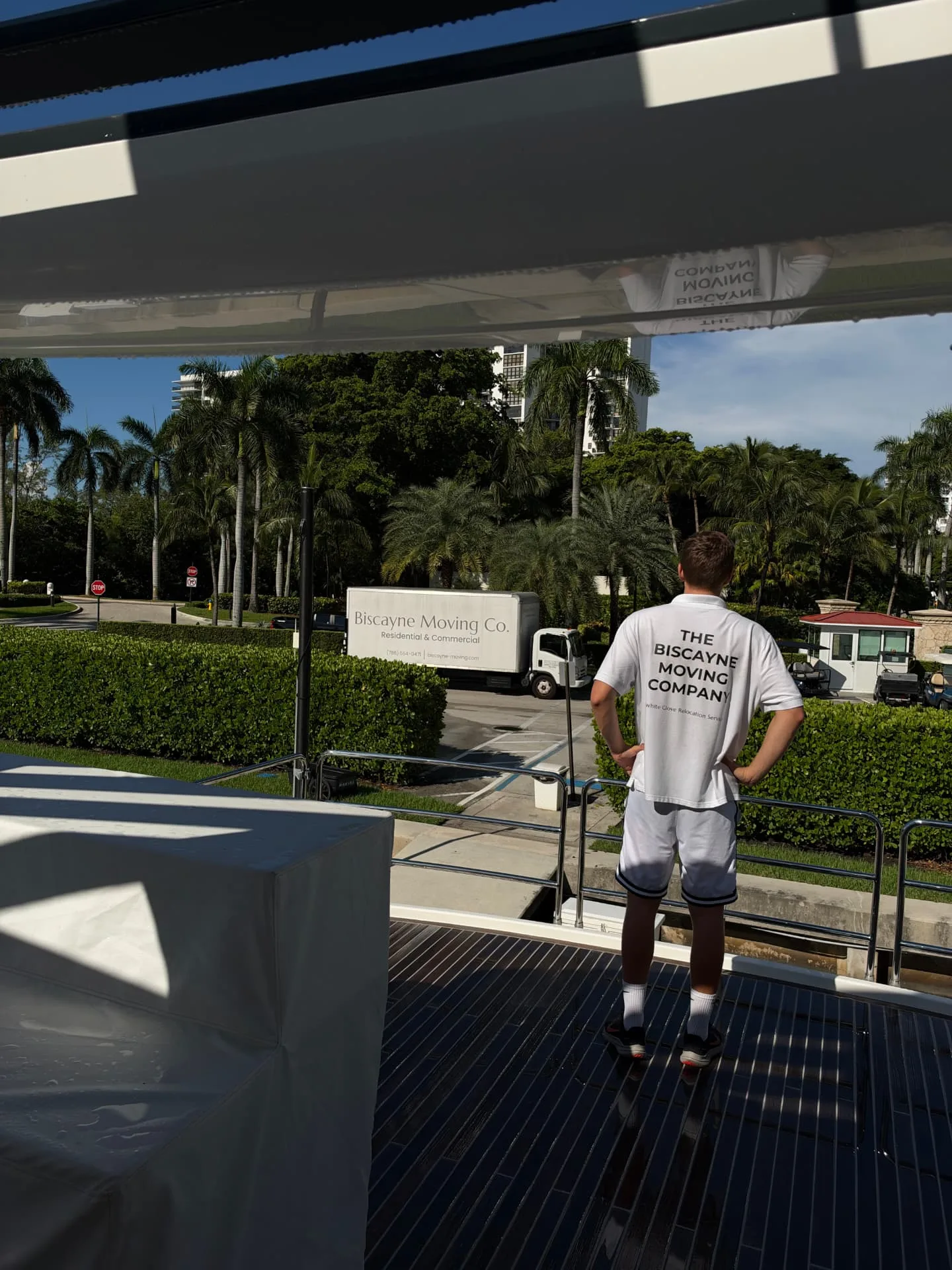 Biscayne Moving Co. crew member watching the truck from a yacht deck at a marina job