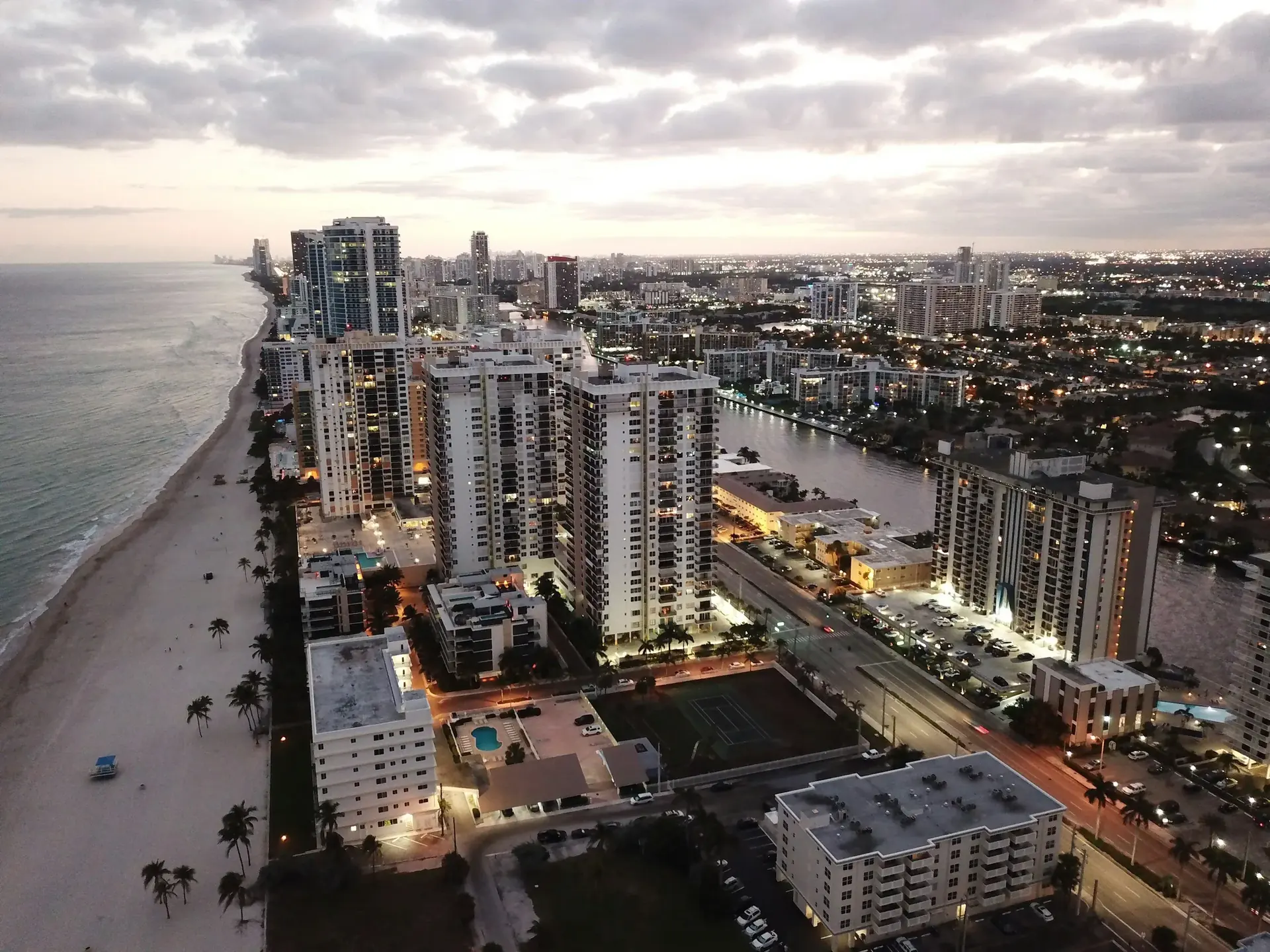 Aerial view of oceanfront condo towers along the beach in Hallandale Beach at dusk