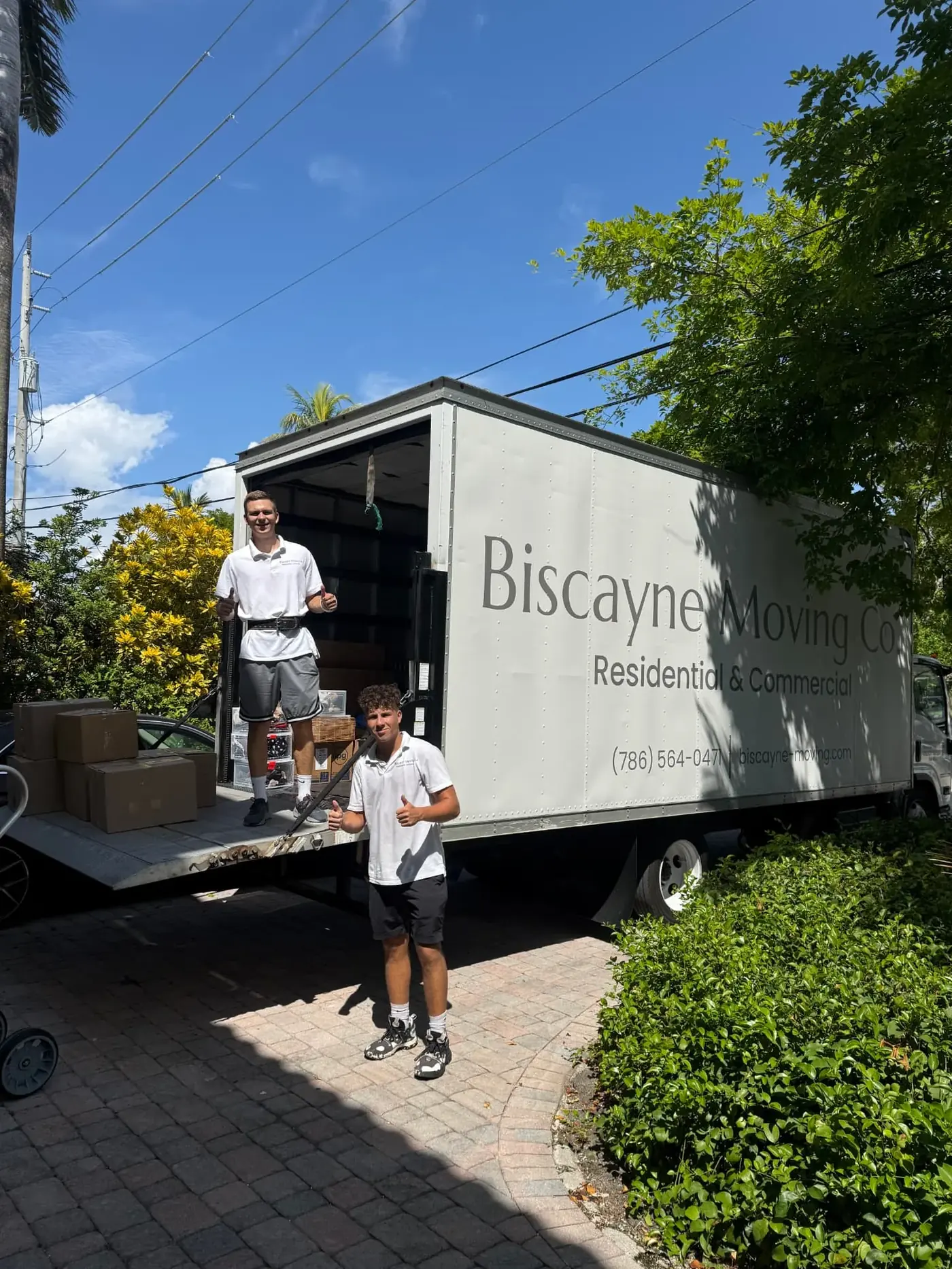 Two Biscayne Moving Co. movers beside boxes on a truck liftgate in West Palm Beach