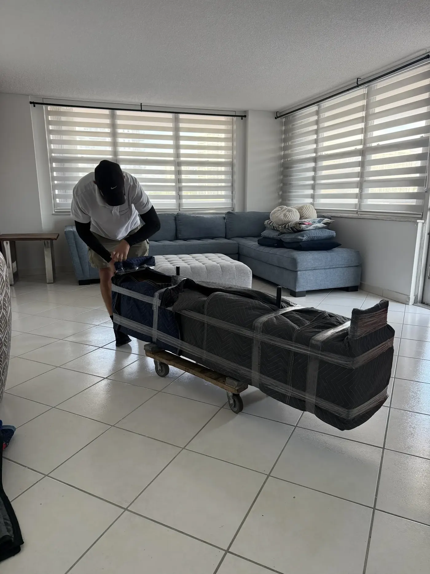 Mover wrapping a sofa with protective film during a Miami packing job