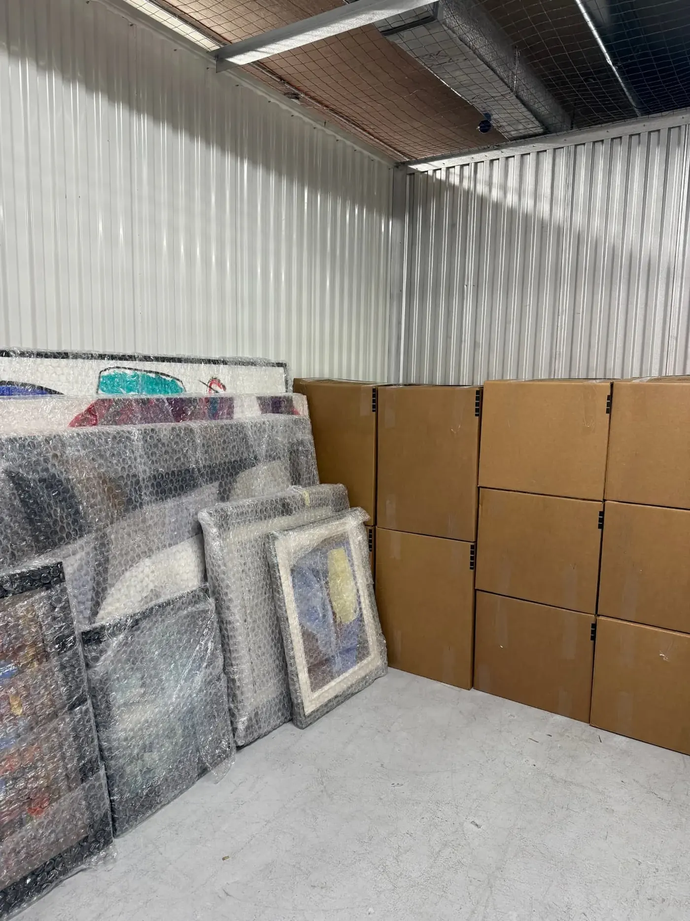 Bubble-wrapped artwork beside stacked boxes during a Miami unpacking project