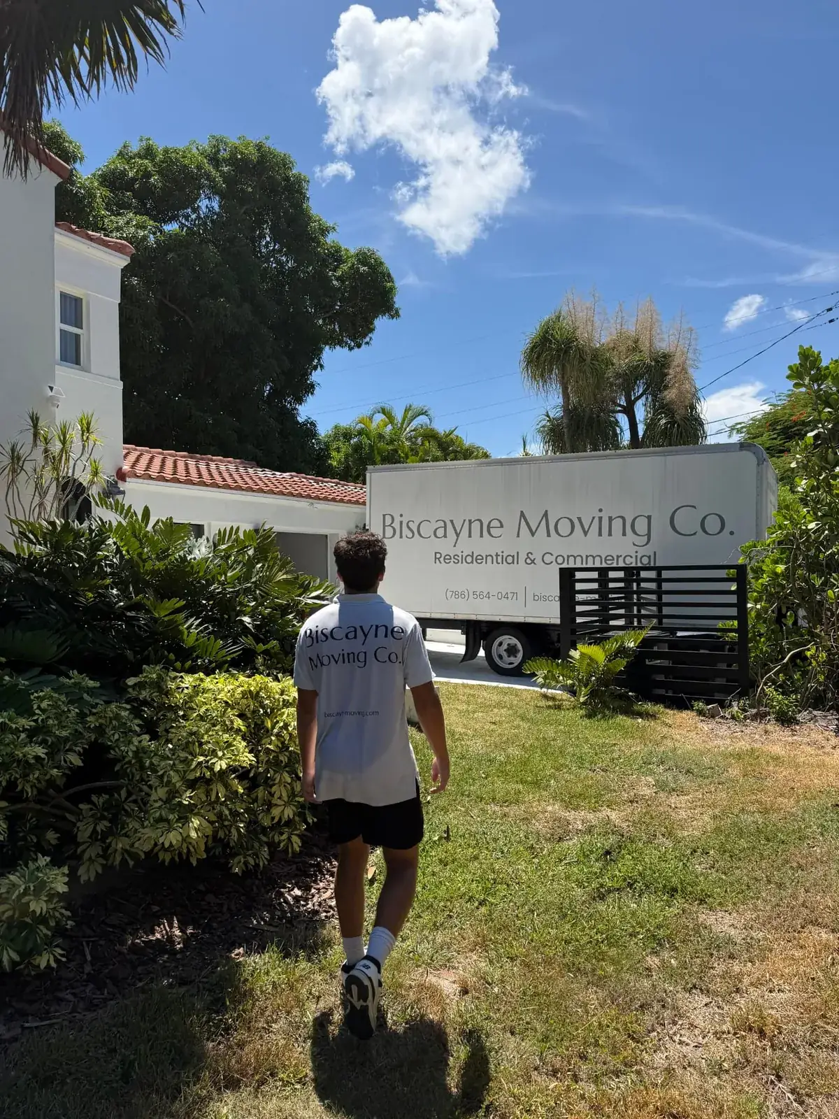Biscayne Moving Co. crew member walking toward the truck outside a Mediterranean-style home during a residential move