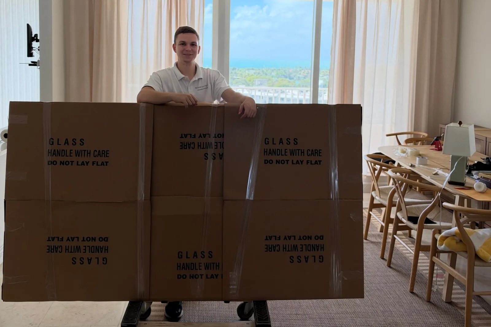 Mover with a large glass piece packed in protective cardboard crating inside an oceanfront Miami Beach condo